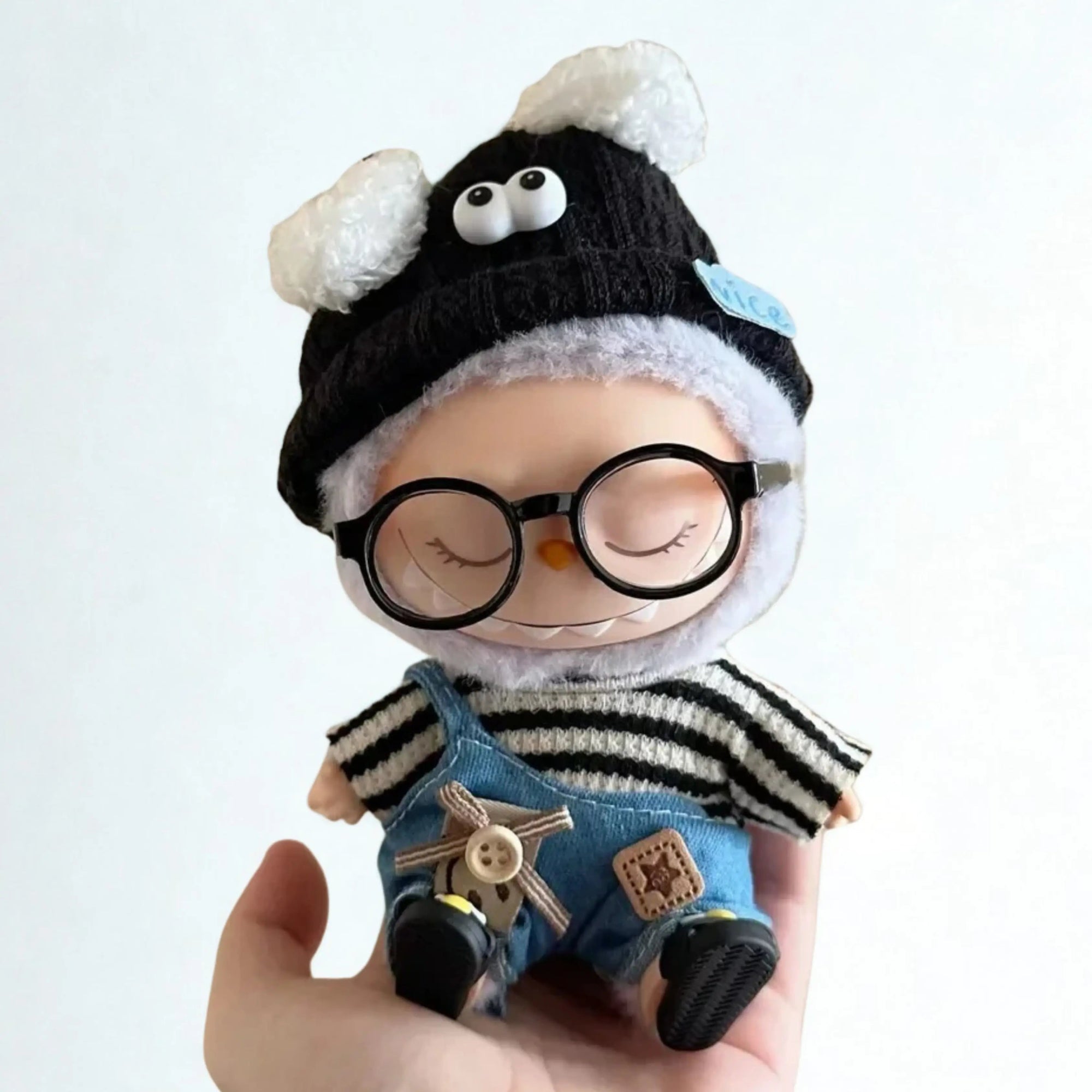 Labubu Popmart com olhos fechados usando touca fofa preta, jardineira jeans e óculos, kit completo de roupa casual